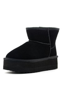 Stivale alla caviglia nero con esterno in suede, punta rotonda e suola piatta nera spessa. Presenta dettagli cuciti lungo le cuciture.