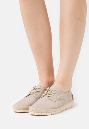 Beige-laadukkaat kengät, jotka on valmistettu pehmeästä mokasta, kudotulla juuttireunalla ja kevyellä kumipohjalla. Ominaisuuksiin kuuluvat pyöreä varvas ja teksturoitu pinta.