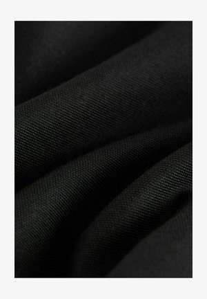 Črn tkanine z pleteno površino, ki prikazuje mehke gube in enotno barvo. Tkanina ima gladek, trpežen občutek.