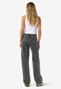 Grå höga jeans med avslappnad passform, blekt denimtextur, två bakfickor och raka ben. Modellen visas från baksidan.