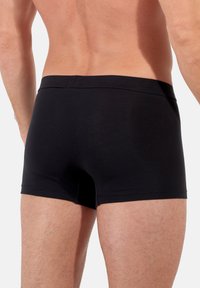 Svarta boxershorts med en åtsittande passform, tillverkade av mjukt tyg. Har en sömlös midja och en enkel, strömlinjeformad design.