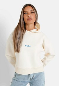 Felpa crema con ricamo blu che dice "Sixth June", caratterizzata da una vestibilità rilassata, cappuccio ampio e orlo a coste. Indossata con jeans in denim chiaro.