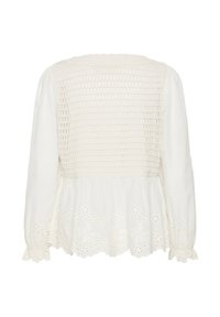 Blouse blanche à manches longues avec dos smocké, ourlet et manches brodés à jour, et poignets volantés.