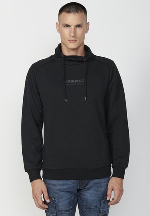 Sudadera negra hecha de tejido texturizado con un patrón de espiga. Presenta un cuello alto, cintas de ajuste y un logotipo tonal de la marca en el pecho.