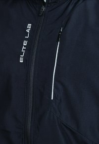 Black athletic jacket with textured fabric, front zipper, and reflective white accents. Features brand name "ELITE LAB" in white lettering.