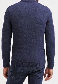 Navyblå stickad tröja med rund halsringning, ribbade ärmslut och nederkant, med en texturerad yta och en klassisk passform.