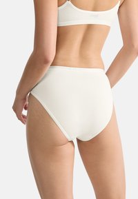 High-waisted, cream-colored underwear made of soft cotton blend. Smooth texture with a wide elastic waistband and minimal seams for comfort.