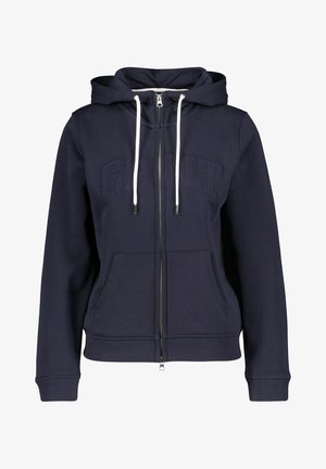 Hoodie zippé bleu marine avec cordons blancs, poches avant, poignets côtelés et logo "GANT" en relief sur la poitrine.