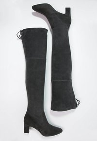 Bottes noires en daim au-dessus du genou avec un talon carré, une texture lisse et des lacets latéraux pour un ajustement réglable. Présentent un design à bout pointu.