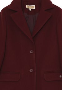 Blazer in lana color bordeaux con colletto a revers, due tasche frontali e chiusura con due bottoni; tessuto liscio e vestibilità su misura.