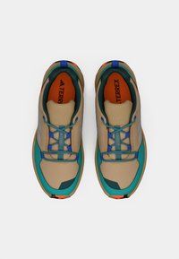 Pantofi sport bej cu accente teal, partea superioară din plasă, șireturi albastre, interior portocaliu și detalii de marcă argintii pe laterale.