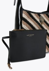 Czarna torebka na patentowanej skórze z plecionym paskowym wzorem w neutralnych odcieniach oraz dekoracyjnym detalem w kształcie pawia w kolorze złotym, zawiera czarną saszetkę na zamek.