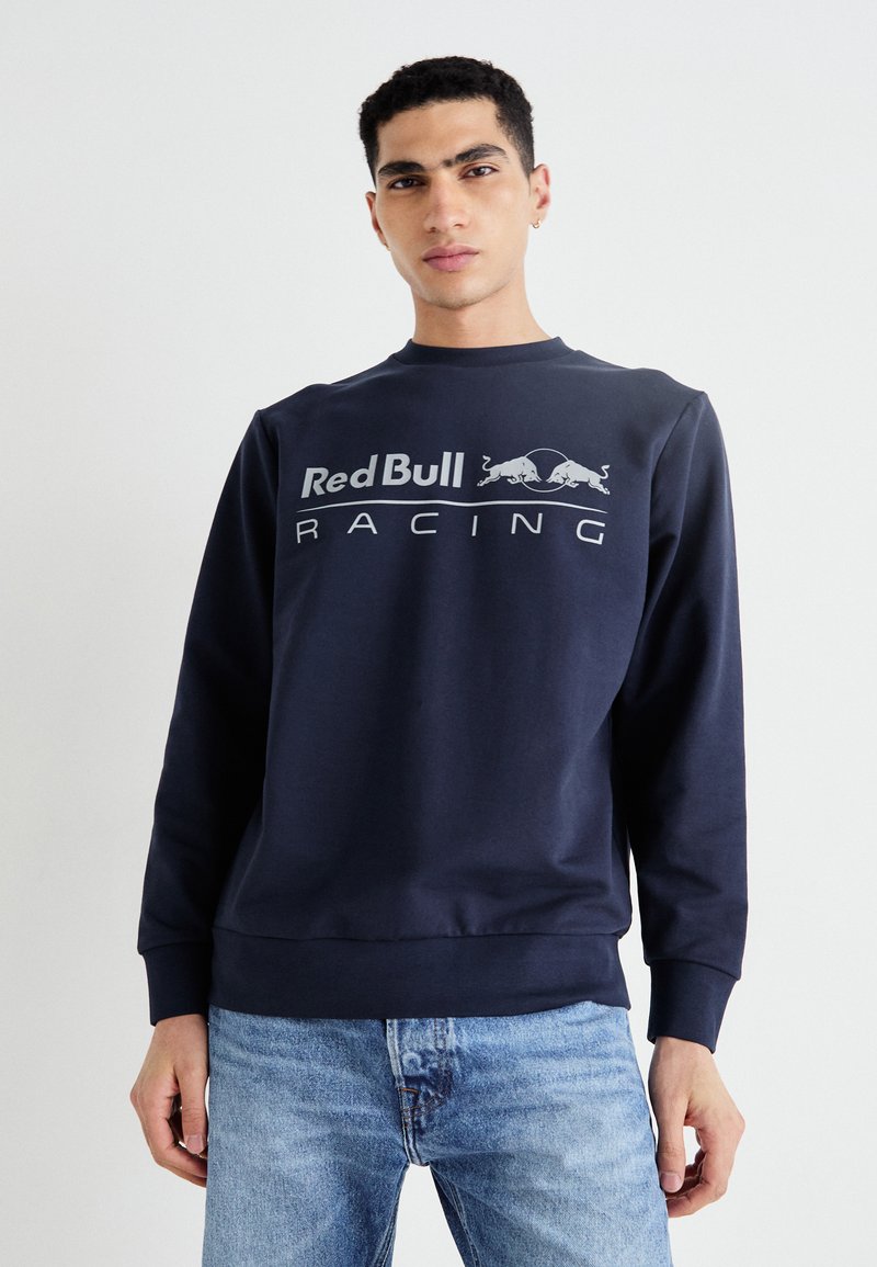 Tamsiai mėlyna ilgomis rankovėmis palaidinė su apvaliu iškirpimu, dekoruota baltu "Red Bull Racing" logotipu. Pagaminta iš minkštos medvilnės mišinio.