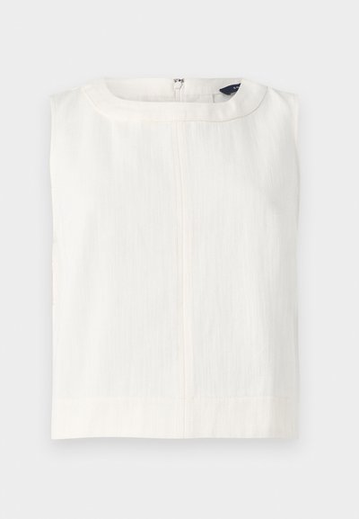 Haut blanc sans manches à texture, avec un col rond et une fermeture éclair au dos, présenté à plat sur un fond gris.