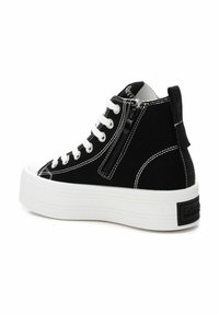 Zapatillas altas de lona negra con suela de plataforma blanca, costuras blancas y cremallera lateral. Presentan una pestaña trasera texturizada con la marca.