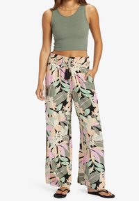 Kevyt vihreä lyhyt tankkitoppi, joka on yhdistetty leveälahkeisiin housuihin, joissa on monivärinen trooppinen lehtikuosi ja joustava vyötärö, jossa on tupsut.