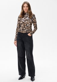 Długi rękaw w panterkę, dopasowany krój, zestawiony z wysokim stanem ciemnogranatowych spodni z szerokimi nogawkami oraz jasnobrązowym paskiem, dopełniony czarnymi botkami.