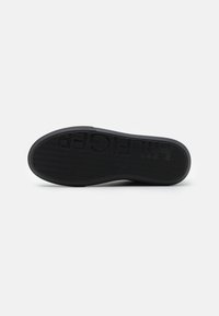 Sole nera di sneaker con un motivo di grip testurizzato. Presenta il logo in lettere in rilievo e un design a bordo liscio per la flessibilità.