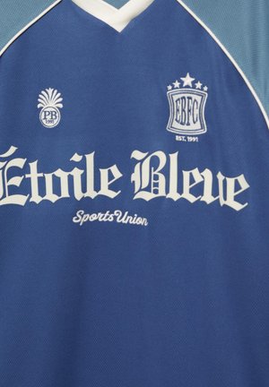Kék sport mez fehér szegéllyel, rajta az „Étoile Bleue Sports Union” felirat és két hímzett logó „PB 1991” és „EBFC EST. 1991” felirattal.