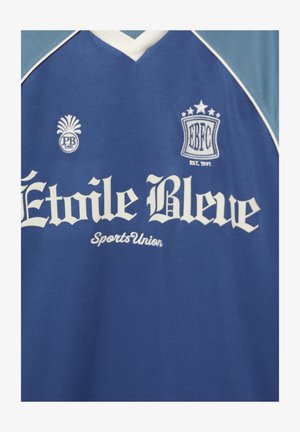 Kék sport mez fehér szegéllyel, rajta az „Étoile Bleue Sports Union” felirat és két hímzett logó „PB 1991” és „EBFC EST. 1991” felirattal.
