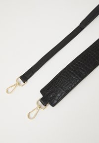 Correa de cuero negro con un patrón de cocodrilo texturizado en una sección más ancha, complementada por clips de hardware en tono dorado.