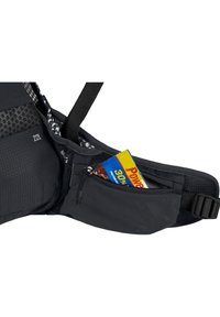 Schwarze Hüfttasche mit einem Reißverschlussfach, in dem ein Proteinriegel sichtbar ist. Hergestellt aus strapazierfähigem Material und mit verstellbarem Gurt. 22L Fassungsvermögen.