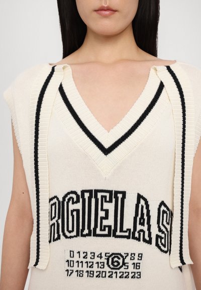 Sleeveless knit top in cream with black stripes along the V-neck and shoulder. Features bold black lettering and numerical pattern.