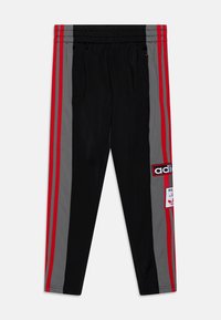 Schwarze Sporthosen mit grauen Seitenpaneelen, roten Streifen, elastischem Taillenbund, Reißverschlusstaschen und Adidas-Logo-Patches am rechten Bein.