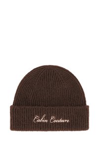 Brun strikket lue med vertikal ribbestruktur, med brettet kant og brodert "Cabin Couture" i lys beige. Myk tekstur.