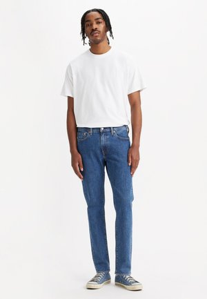 White short-sleeve t-shirt, blue denim jeans, and blue sneakers. Simple design, regular fit, no visible patterns, clean finish.