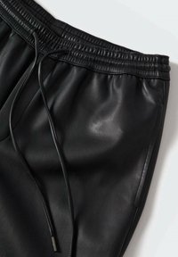 Czarne skórzane spodnie dresowe z elastycznym pasem i sznurkiem. Posiadają gładką, elegancką fakturę oraz boczne kieszenie.