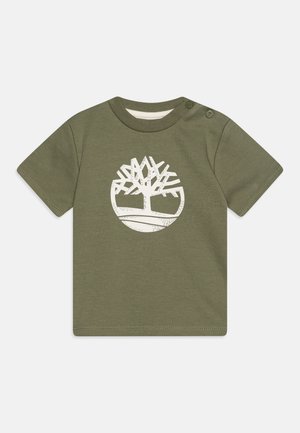 T-shirt en coton olive à manches courtes avec un logo d'arbre blanc sur un design circulaire. Boutons-pression à l'épaule pour un enfilage facile.
