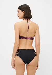 Two-piece bikini set featuring a purple tie-dye halter top and high-waisted black bottoms with side cutouts. Smooth texture, adjustable ties.