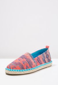 Zamknięty espadryl slip-on z koralowym, purpurowym i niebieskim tkaninowym wierzchem, jasnoniebieskim wnętrzem oraz plecioną juty podeszwą na białym tle.