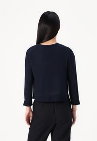 Navy blue cropped sweater in soft knit fabric, featuring a round neckline and three-quarter sleeves with ribbed cuffs.