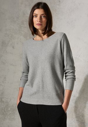 Grijze geribde trui met een brede halslijn, aansluitende mouwen en een subtiele textuur, gestyled met donkere broek. Eenvoudig ontwerp, neutrale tinten.