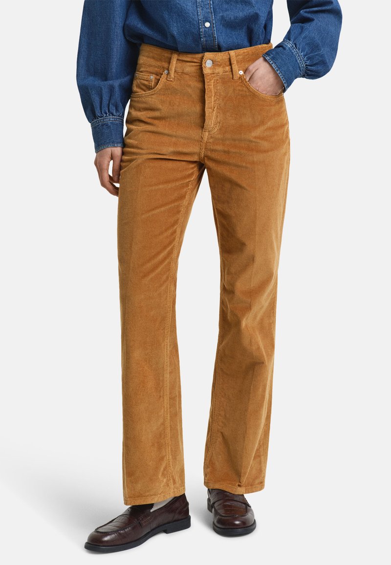 Bruine corduroy broek met brede pijpen, met een hoge taille, voorzakken en knoopsluiting. Getextureerde stof met verticale ribbels.