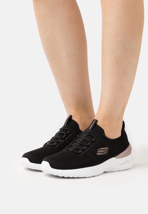 Zapatos deportivos de punto negros con suela blanca, con diseño de calzado sin cordones, cordones elásticos y un sutil detalle en oro rosa en el talón.