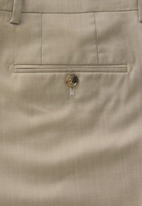 Pantalon beige avec une texture lisse, présentant une poche arrière avec un bouton et des détails de couture. Design ajusté et finition élégante.