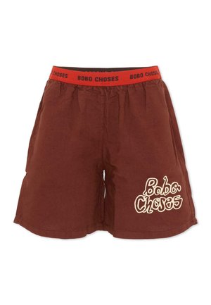 Brązowe szorty z czerwonym elastycznym pasem z napisem „BOBO CHOSES” oraz białym napisem „Bobo Choses” na dolnej prawej nogawce.
