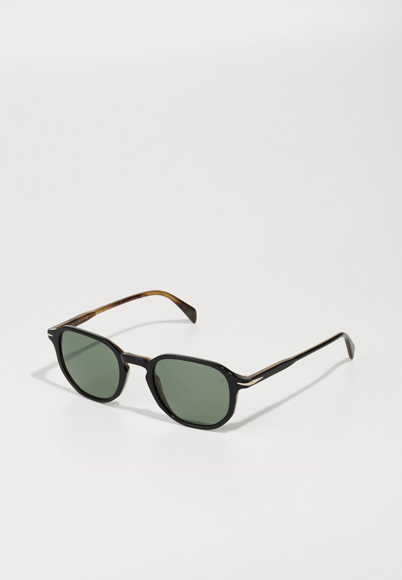 Óculos de sol com armação preta e tartaruga, lentes verdes, formato hexagonal e detalhes em metal fino nas hastes.