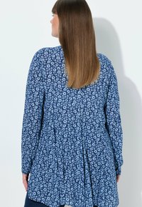 Niebieska bluzka z długim rękawem z plisowanym tyłem. Posiada drobne białe kwiatowe wzory na ciemnoniebieskim tle. Miękka faktura materiału.