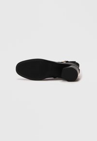 Svart sandaler med strukturert overdel, ankelreim og kraftig hæl. Gummis�åle med mønstret grep for godt feste. Minimalistisk design.