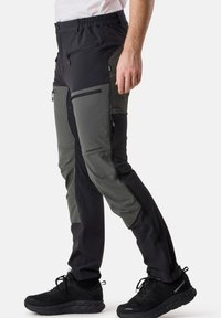 Schwarze und olivgrüne Wandhose mit elastischem Bund, mehreren Reißverschlusstaschen und einer schmal zulaufenden Beinform. Leichtes, strapazierfähiges Material.