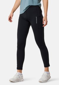 Leggings sportivi neri con una texture liscia, dotati di una tasca laterale, design slim fit e un accento con il logo bianco sulla coscia.