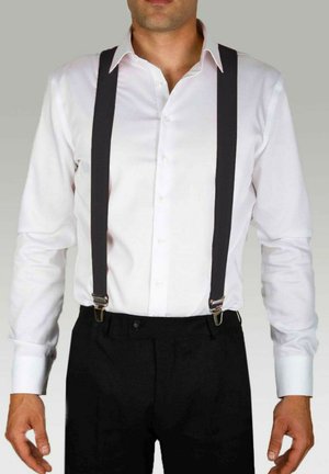 Chemise blanche à manches longues avec des bretelles gris foncé comportant des clips métalliques, portée sur un pantalon noir. Apparence propre et ajustée.
