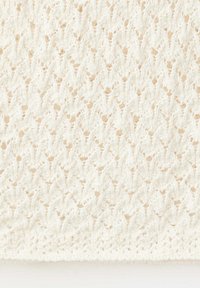 White knitted fabric with a textured diamond pattern and small openwork details, showcasing soft yarn and intricate stitching.