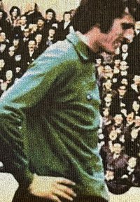 Groene gestructureerde shirt van ribstof, met een hoge kraag en een nauwsluitende silhouet, met een onduidelijke menigte op de achtergrond.