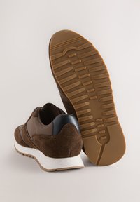 Baskets en daim marron et nylon avec une semelle intermédiaire en mousse blanche et une semelle extérieure en caoutchouc, présentant un motif texturé et un maintien rembourré de la cheville.