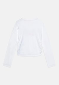 Biała, długa spódnica crop top z miękkiego materiału, z okrągłym dekoltem i lekko marszczonym detalem po bokach.